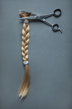 Chopped off blond braided hair on a grey background