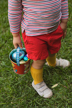 A young toddler boy has a chocolate easter egg hunt in his backyard in Australia