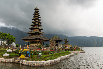 Obraz premium Bali, Indonesia - February 25, 2019: Ulun Danu Beratan Temple complex in Bedoegoel. Tengahing Segara temple is pagoda of eleven levels with adjacent shrine, all on island under rainy cloudscape. Green