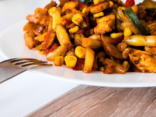 Vegetables with fried chicken on white plate.