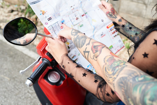 Crop of girl pointing at map sign on red motorbike.