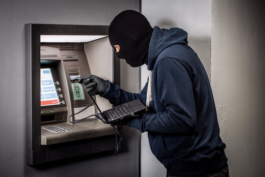 Hacker stealing password and identity on atm machine. Computer crime concept.