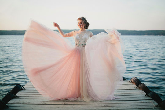 Beautiful model posing in wedding dress on a pier