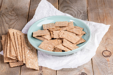 Corn airy crispbreads on round plate and on white wrapping paper on wooden table. 
