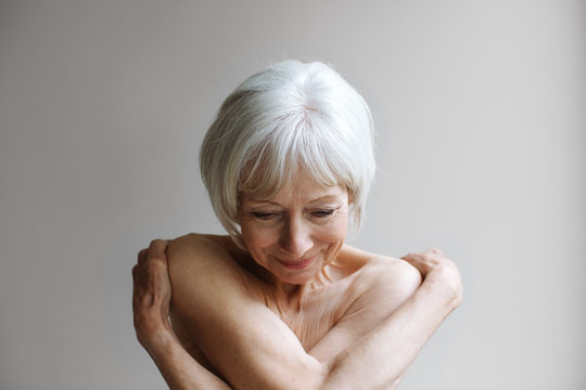 Portrait of naked senior woman against gray background