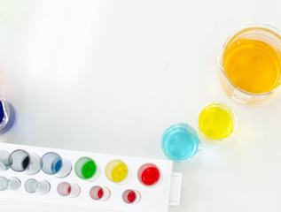 top view of laboratory equipments. A blue liquid watch glass, flask, test tubes and beaker on the white table