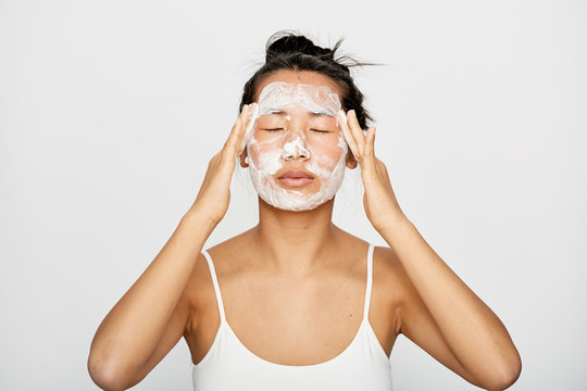 Young beautiful Asian woman washing her face