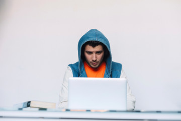 Front view of a young man casual clothing sitting while using a computer