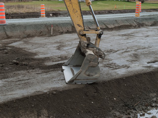 Road work excavator using the bucket of the excavator to smooth the surface of the road in order to...