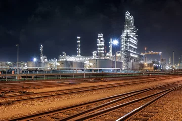  illuminated oil refinery at night with rail tracks on the foreground, Port of Antwerp, Belgium. © tonyv3112