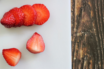 Strawberries on a white cutting board on a wooden background