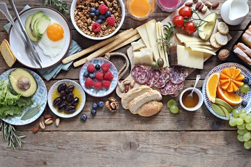 Brunch or breakfast set, meal variety with fried eggs, sausage and cheese variety, granola, smoothie, fruits and berries. Overhead view