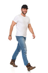 Walking Man In White T-shirt, Jeans, Boots And Black Cap