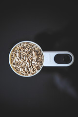 Natural sunflower seeds without shell in the white measuring cup taken from the top on the back background.