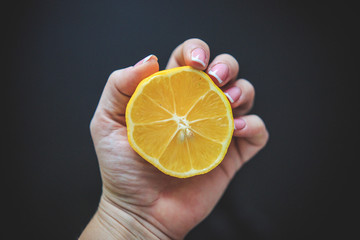 Meyer lemon half of orange color originating in China taken in hand from up on the black background.