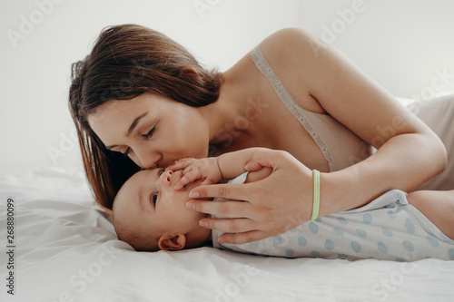 Cute baby boy playing with his mum on the bed