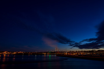 The Harbor Bridge in Saint John, New Brunswick, shortly after sunset. The sky is dark blue with some cloud, and smoke from the pulp mill is visible. The view is from across the harbor. Room for text.