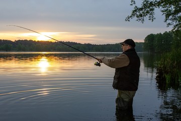 Silhouette of angler catching the fish during sunrise