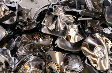 A pile of hard drive that were crushed to destroy their data. Mostly the platters are visible, these are bent and twisted. Focus is on the coils near the middle left.