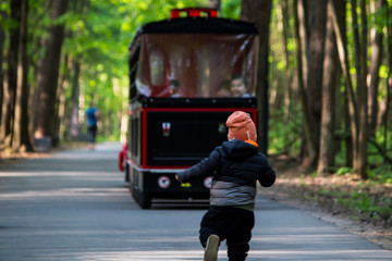 little boy catching up with train in park