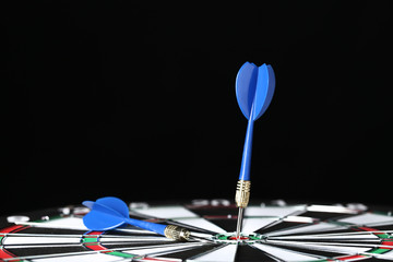 Dartboard with darts on black background
