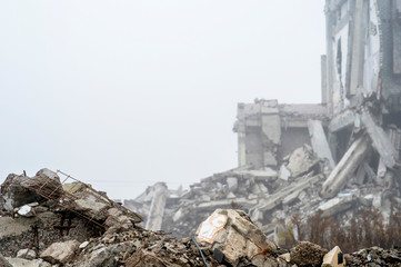 The remains of concrete fragments of gray stones on the background of the destroyed building in a...