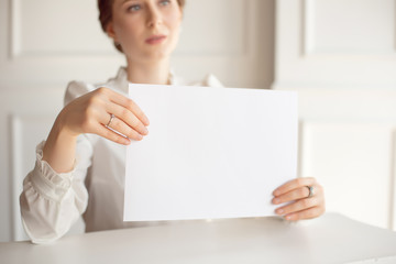 Woman holding white business card on white wall background