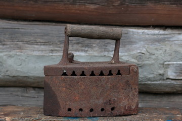Rare iron working on coals.  It stands on the background of an old wooden barn.