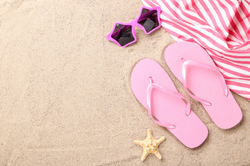 Fototapeta na wymiar Pair of flip flops with starfish and sunglasses on beach sand