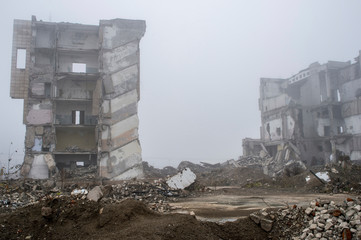 The remains of concrete fragments of gray stones on the background of the destroyed building in a...