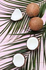 Ripe coconuts with palm leafs on pink wooden table