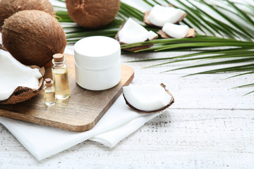 Coconuts with oil in bottles and palm leafs on wooden table