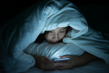 Asian woman play smartphone in the bed at night,Thailand people