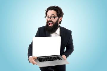 Man with blank laptop computer screen, cheerful young bearded man holding laptop and smiling over blue background