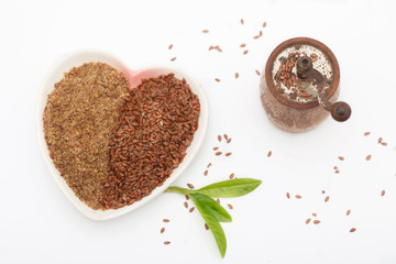 Whole and ground or crushed brown flax seed or linseed with grinder on white vackground. Healthy food for preventing heart diseases and overweight.