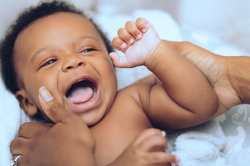 Mother's hands hold laughing baby