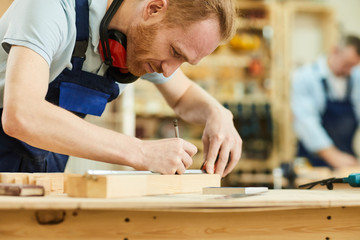 Cropped portrait of contemporary carpenter working with wood standing at table in workshop, copy space