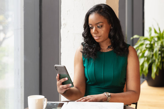 Businesswoman with black hair looks at phone