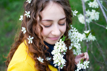 Naklejka premium Happy young woman enjoying smell flowers over spring garden background