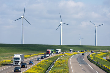 Dutch motorway near Lelystad with wind turbines and blooming rapeseed - obrazy, fototapety, plakaty
