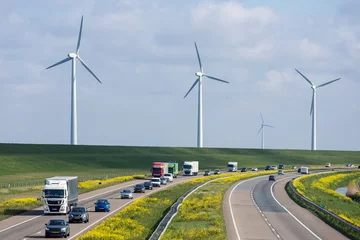 Foto op Plexiglas Dutch motorway near Lelystad with wind turbines and blooming rapeseed © Kruwt