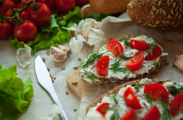 bruschetta with curd cheese cherry tomatoes greens and garlic on the table and bread