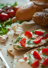 bruschetta with curd cheese cherry tomatoes greens and garlic on the table and bread