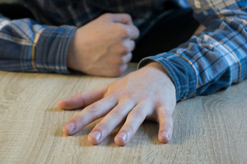 hand of an adult man lying on a wooden table