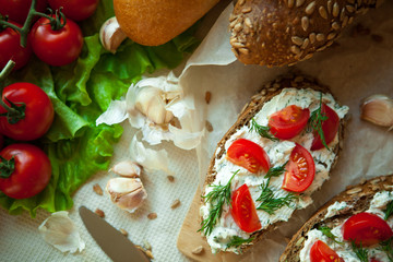 bruschetta with curd cheese cherry tomatoes greens and garlic on the table and bread