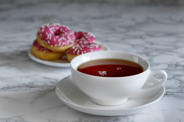 A cup of tea and a saucer with donuts