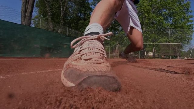 Tennis player on a clay court sliding to reach a ball