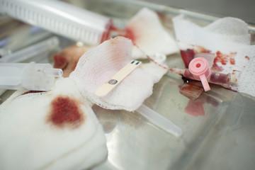 syringes and gauze on a medical tray after surgery