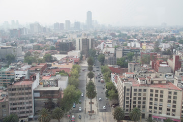 Calle vista desde el Monumento a la Revolución con la ciudad de México contaminada como fondo