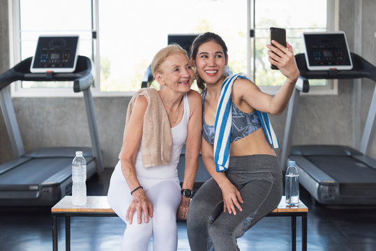 Women attractive smiling active fitness couple sitting in gym and taking a selfie.